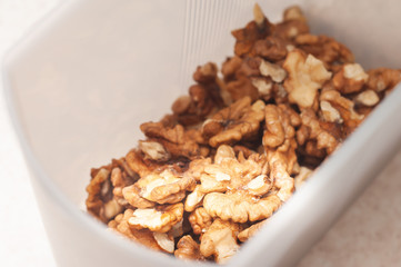 Close-up peeled walnut kernels in a plastic storage container