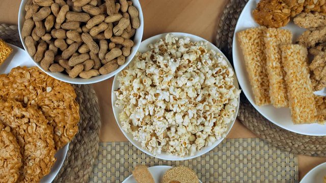Tilt shot of various Lohri items beautifully plated on a wooden table - festive scene. Top view shot of dry fruits gajak  rewri  gajak rolls  popcorns  peanuts chikki  roasted groundnuts  murmura l...