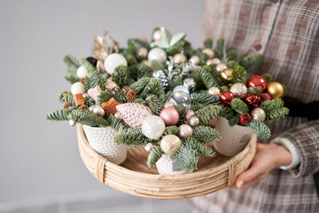 Florist holds a tray with christmas arrangements. Beautiful festive arrangement of fresh spruce in coffee Cup. Christmas mood.