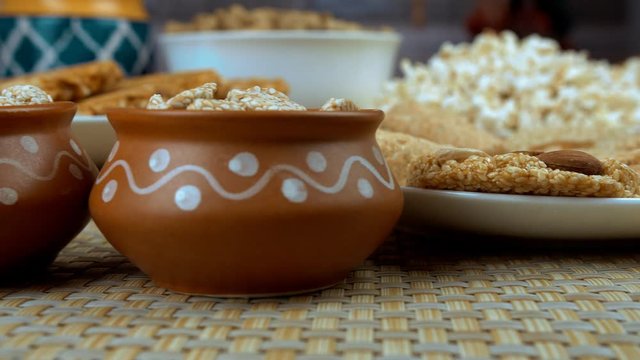 Closeup shot of edible items consumed during the Lohri and wintertime in India. Pan shot of various Lohri items like  til patti  rewri  popcorns  peanuts chikki  gajak rolls  etc placed on the dini...