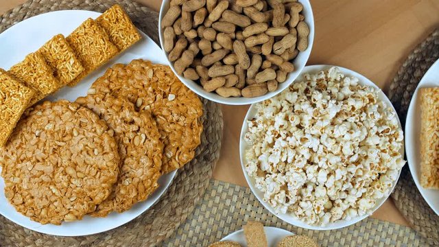 Pan shot of delicious Lohri items consumed during the winter season in India. Top view shot of peanuts chikki  popcorns  bhujia chikki  gajaks  murmura chikki  and ladoos beautifully placed on a wo...