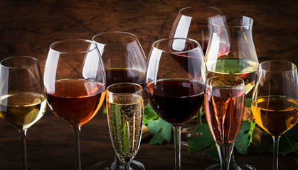 Wine tasting concept, still and sparkling wines. Red, white wine, rose and champagne in wine glasses on vintage wooden table background