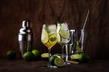 Mojito cocktail with lime and mint in wine glass on wooden background. Copy space