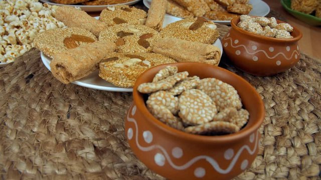Closeup shot of gajak rolls  til patti  and rewri rotating on a turntable - Lohri festival. Beautifully plated rewris  gajak rolls  and til patti surrounds by popcorns  peanuts chikki  murmura lado...