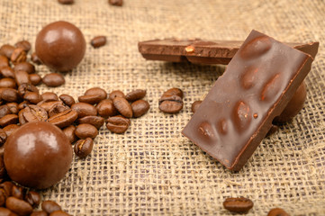 Coffee beans and chocolate on a background of rough homespun fabric. Close up.