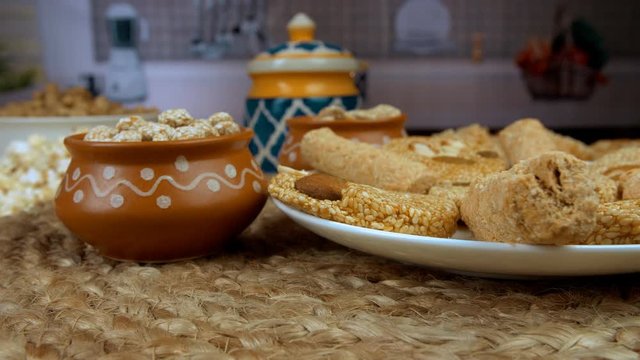 Beautifully plated Lohri items consumed during the winter season on Lohri in India. Closeup shot of til patti  gajak rolls  and rewri rotating on a turntable surrounded by popcorns and groundnuts a...