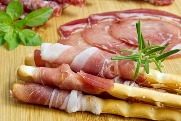 Meat and cheese plate antipasti snack with Prosciutto ham, Parmesan, Blue cheese, Cantaloupe melon and Olives on olive wood serving board on dark stone background