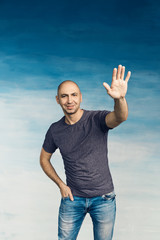 Attractive bald man on a blue background raised his left hand up with his  palm up for greetings, ...