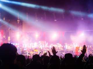 crowd at concert - summer music festival in front of bright stage lights. Dark background, smoke, concert spotlights.people dancing and having fun in summer festival