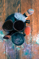 Make-up brushes in a cup on wooden background. Top view. 