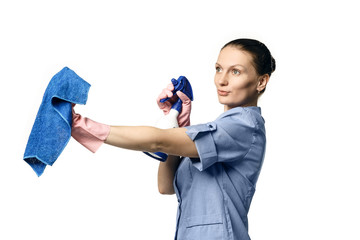 A  woman in the uniform of a maid holds a rag and spray for washing windows and looks at them in surprise. Isolated on a white background. Washes glass