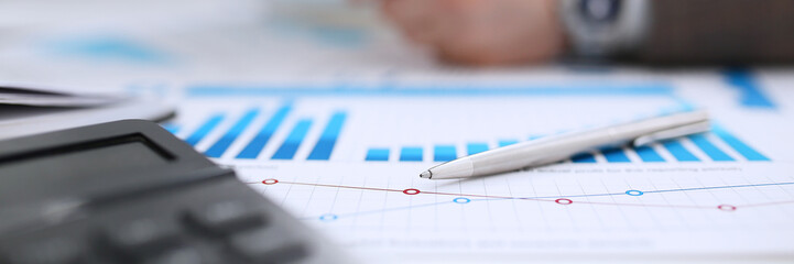 Black calculator and financial statistics on clipboard pad