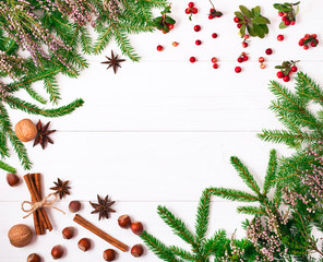 Christmas fir tree and heather decoration, fir cones and red berries on a white wooden background. Top view. Copy space.