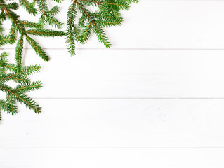 Christmas greeting card. Text space. Fresh fir tree branches on a white wooden background. Top view.