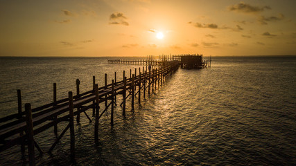 Fototapeta na wymiar Sunset over a long dock (pier) in the ocean in Zanzibar, Tanzania