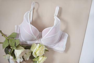 White bra on the beige background with a bouquet of flowers