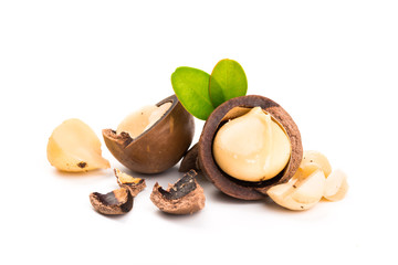 Macadamia nut with pieces and green leaves isolated on a white background