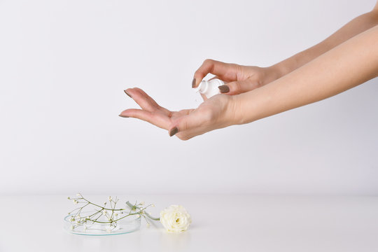 Hands Applying Skincare Moisturizer Oil. Woman Holding A Cosmetic Bottle Containers, Blank Label For Beauty Product Branding Mock-up.