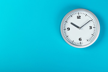White wall clock with a yellow used hanging on the wall. Minimalist image of a wall clock on a blue background with copy space