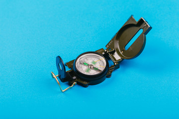 metal navigation travel compass on a blue background. search for a way. point of view