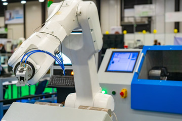 Robot hand on the background of a technical laboratory. Industrial manipulator. Setting up work for turning operations. Robotics at work. Production automation. Robots in the workplace.