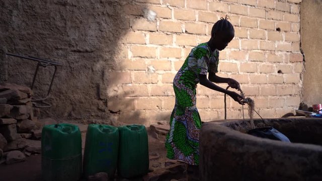 Small African Girl Pulling Up Water At The Village Well
