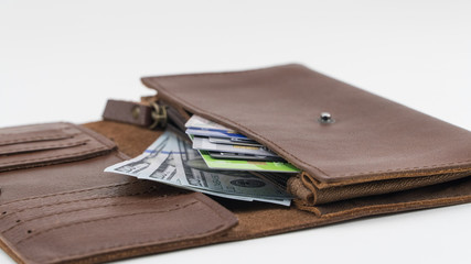 Brown wallet with credit cards and hundred dollar bills on white background