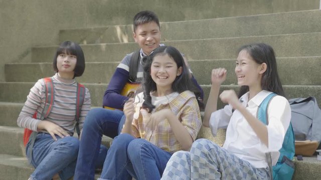 Group of asian teenager sitting in park and giving high five with friends,slow motion shot.