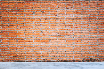 Outdoor concrete floor texture with red bricks wall background.