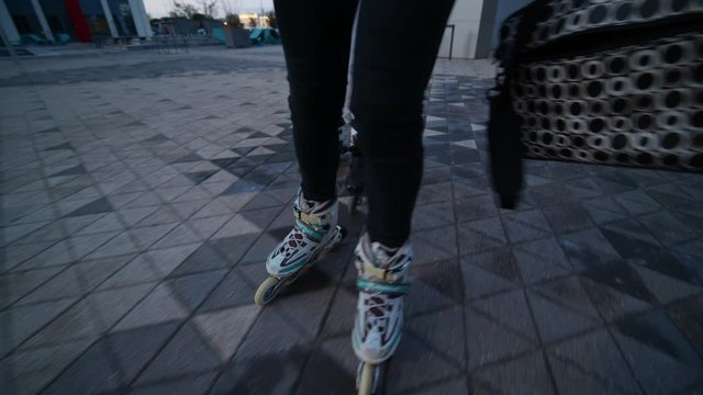 Moving shot of two woman rollerskating while holding computer bags