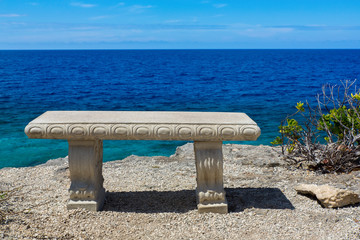 Concrete bench at coast with blue sea