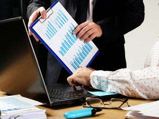Business team works. The boss shows the financial graph in the report to the employee.