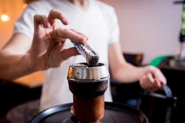 Cooking hookah in the bar. Young man with hookah in restaurant, hookah bar, smoking cafe.