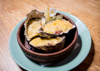 Fresh oysters under cheese on a plate with ice and flowers. Restaurant