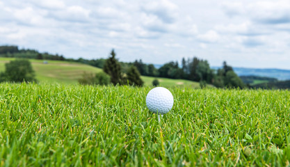 Golfball abschlagsbereit auf einem Tee 