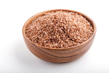 Wooden bowl with unpolished brown rice isolated on white background. Side view.