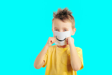 Little child holding a card with smiling face. Boy chooses an emotional faces.