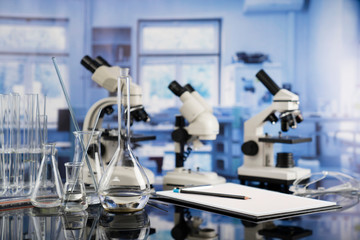 Modern scientific laboratory interior. Laboratory glassware and microscope on the glass table.