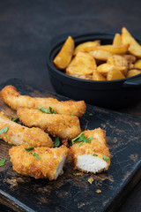 Crispy chicken and potatoes on dark table