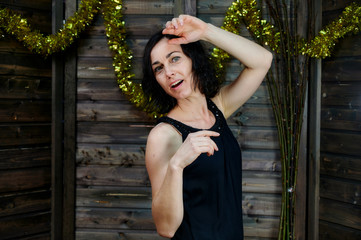 Portrait of a pretty smiling brunette woman in black dress on wooden background in vintage festive...
