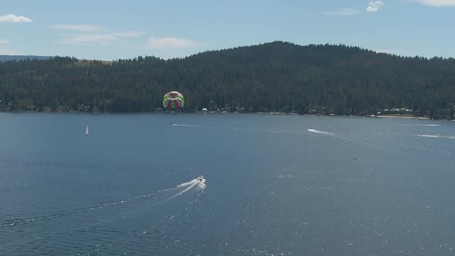 Aerial panning shot behind a parasail over Lake Coeur d'Alene on a beautiful summer day.