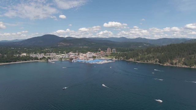 Aerial shot flying towards Coeur d'Alene Idaho with boats and watercraft enjoying the lake on a summer day.