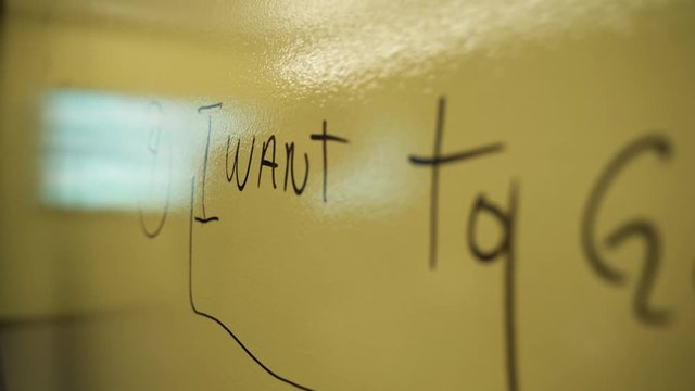 Macro shot of writings on a yellow board. It is a Language class in session at a University.