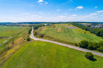 Summer rural landscape, aerial view. View of the village, green fields, and road