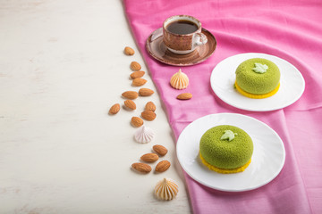 Green mousse cake with pistachio cream and a cup of coffee on a white wooden background. side view, copy space.