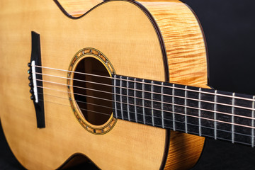 Fototapeta na wymiar wood texture of lower deck of six strings acoustic guitar on black background. guitar shape