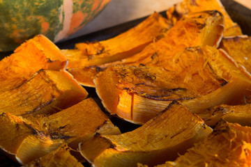 Pieces of baked pumpkin on pan near the pumpkin
