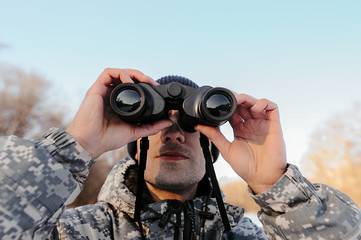 close-up face of a man with bristles and camouflage clothing, a tourist looks at winter nature...