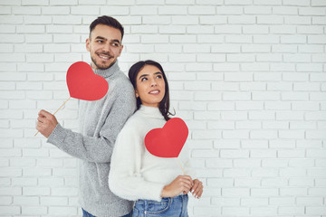 Concert Valentine's Day. Young couple with hearts in hands on a white brick background