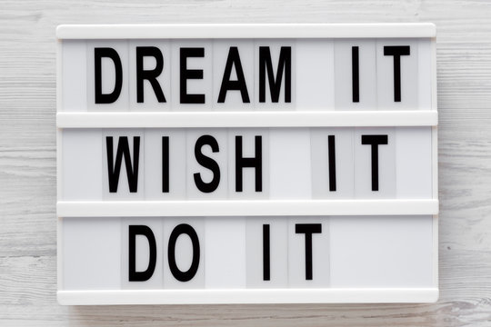 'Dream it, wish it, do it' words on a modern board on a white wooden surface, top view. Overhead, from above, flat lay. Close-up.